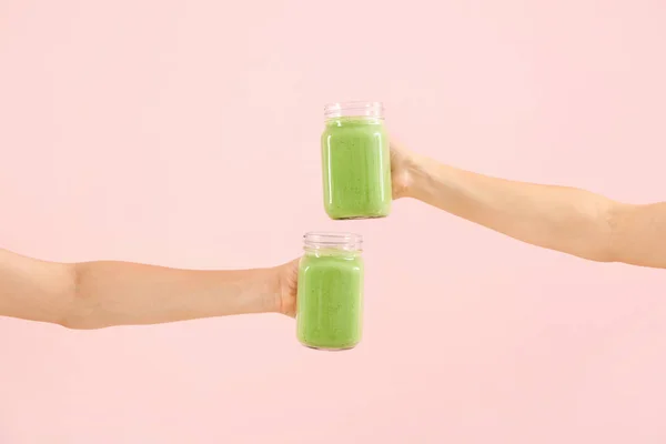 Mãos femininas com saboroso smoothie verde em frascos de pedreiro no fundo de cor — Fotografia de Stock