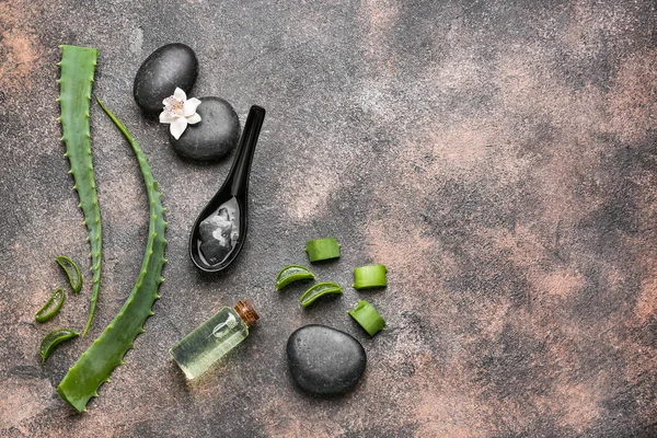 Bottle of essential oil with aloe flesh and leaves on grey background — Stock Photo, Image