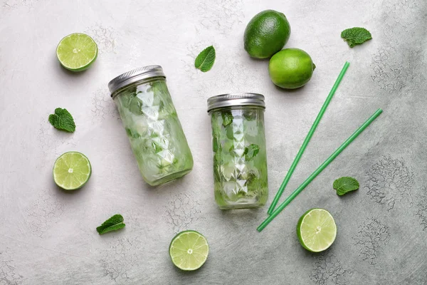 Jars of fresh infused water with lime on light background — Stock Photo, Image