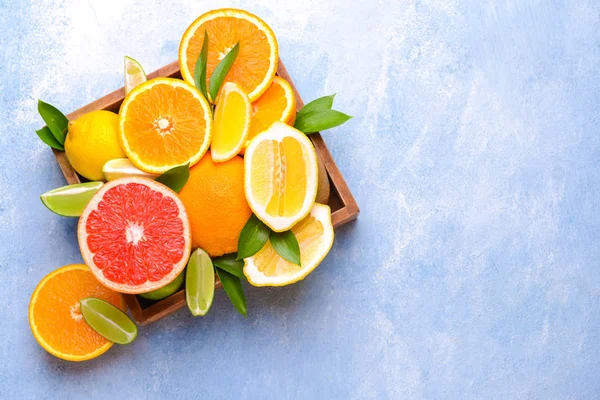 Box with different citrus fruits on color background — Stock Photo, Image