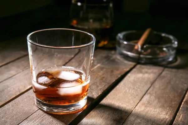Glass of cold whiskey with ice on wooden table — Stock Photo, Image