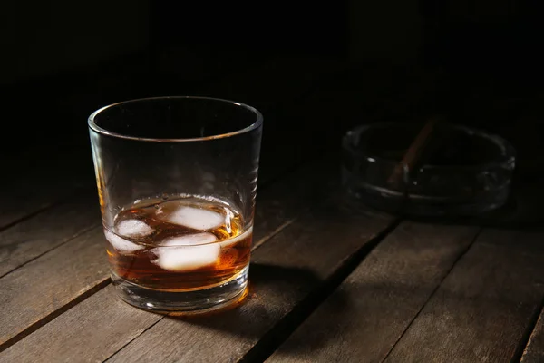 Glass of cold whiskey with ice on wooden table — Stock Photo, Image