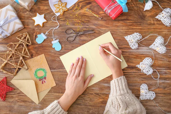 Mujer escribiendo algo en una hoja de papel en una mesa de madera. Celebración de Navidad — Foto de Stock