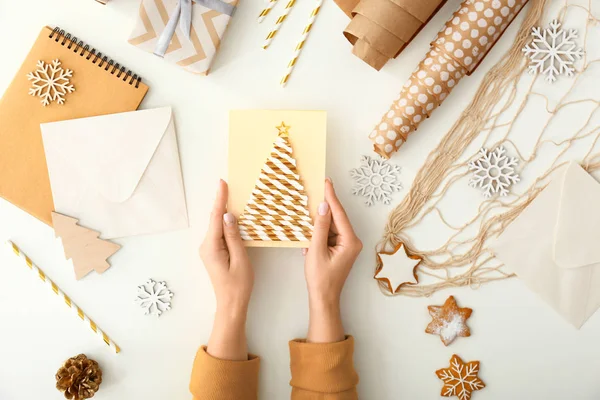 Ženská ruka s kreativní vánoční kartou na bílém pozadí — Stock fotografie