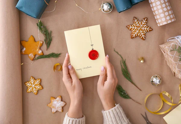 Руки женщины с творческой рождественской открыткой на бумажном фоне — стоковое фото