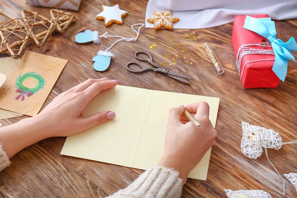 Женщина пишет что-то на листе бумаги за деревянным столом. Праздник Рождества — стоковое фото