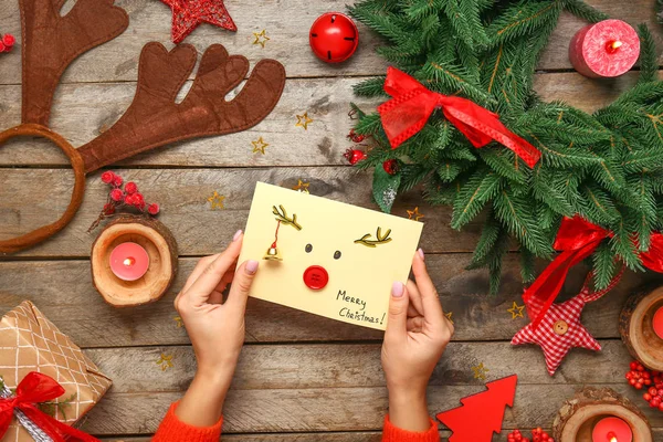 Female hands with creative Christmas card on wooden background — Stock Photo, Image