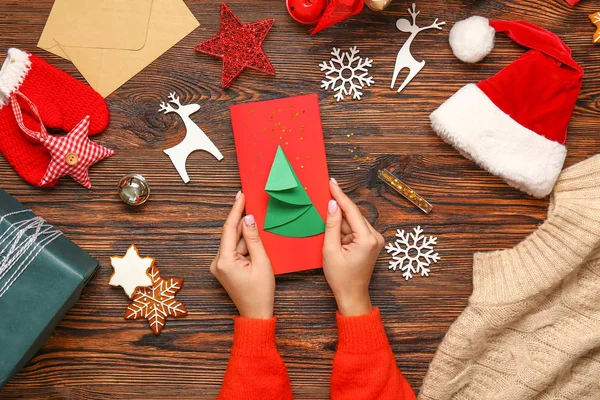 Female hands with creative Christmas card on wooden background — Stock Photo, Image