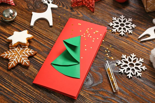 Ręcznie robione kartki świąteczne z ozdobą na drewnianym tle — Zdjęcie stockowe