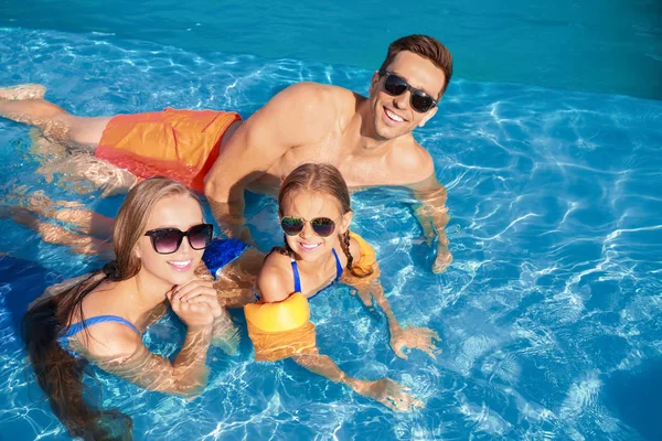 Família feliz na piscina no dia de verão — Fotografia de Stock