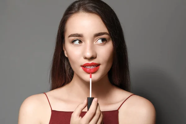 Beautiful young woman with bright lipstick on grey background — Stock Photo, Image