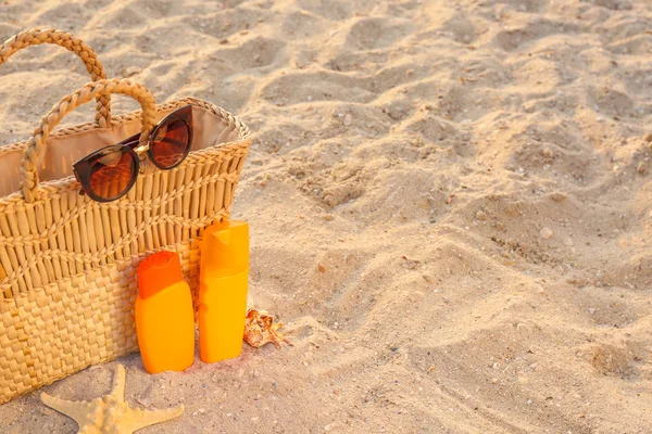 Bag with sunscreen cream and sunglasses on sand beach — Stock Photo, Image