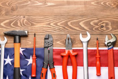 Ahşap arka planda bir takım aletler ve Amerikan bayrağı. İşçi Bayramı kutlamaları