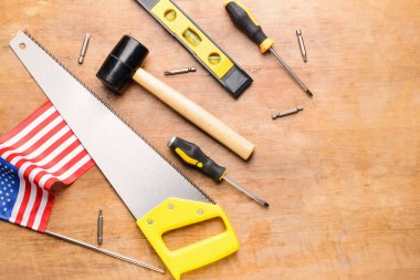 Ahşap arka planda bir takım aletler ve Amerikan bayrağı. İşçi Bayramı kutlamaları