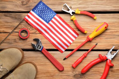 Ahşap arka planda bir takım aletler ve Amerikan bayrağı. İşçi Bayramı kutlamaları
