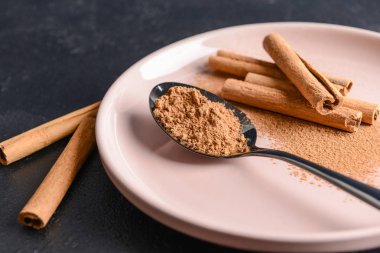 Tarçın tozu ve plaka üzerinde sopa ile Kaşık, closeup