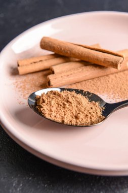 Tarçın tozu ve plaka üzerinde sopa ile Kaşık, closeup