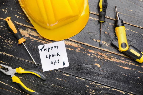 Conjunto de herramientas y tarjeta con texto HAPPY LABOR DAY sobre fondo de madera oscura —  Fotos de Stock