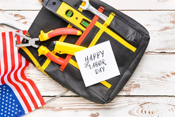 Set of tools, card with text HAPPY LABOR DAY and USA flag on wooden background