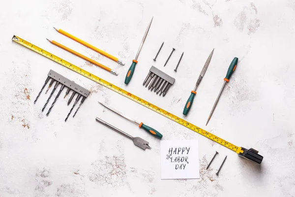Set of tools and card with text HAPPY LABOR DAY on light background