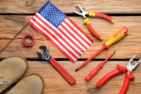 Ahşap arka planda bir takım aletler ve Amerikan bayrağı. İşçi Bayramı kutlamaları