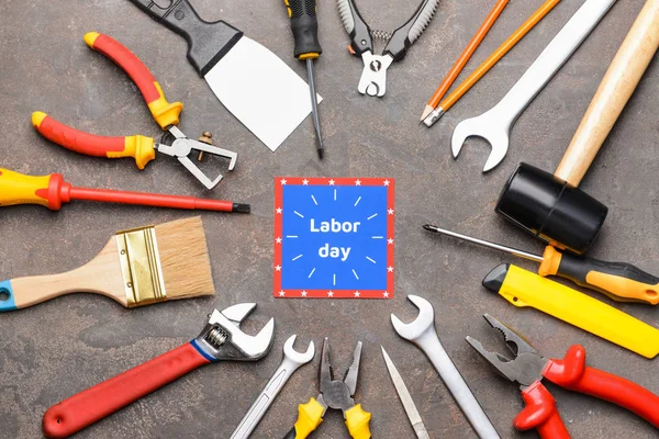 Set of tools and card with text LABOR DAY on grey background