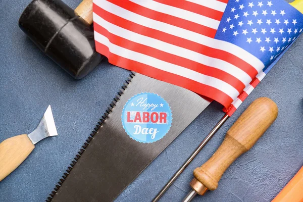 Conjunto de herramientas, bandera de EE.UU. y tarjeta con texto FELIZ DÍA DE LABOR sobre fondo de color — Foto de Stock