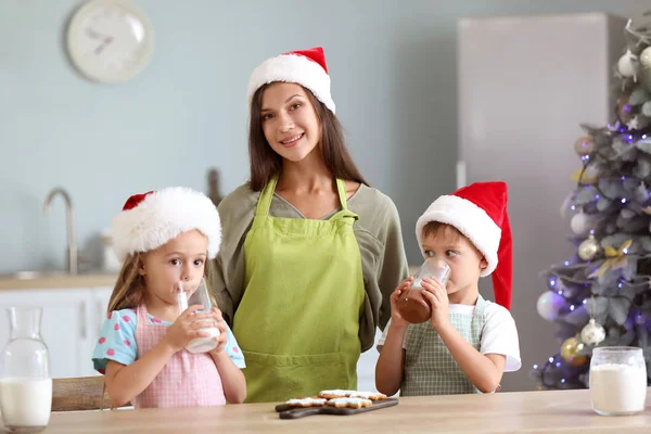 Mulher e seus filhos com biscoitos de Natal, chocolate quente e leite na cozinha — Fotografia de Stock
