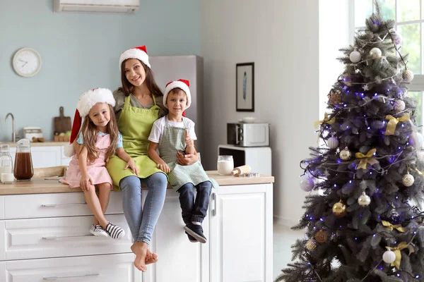 Mulher e seus filhos pequenos depois de preparar biscoitos de Natal na cozinha — Fotografia de Stock