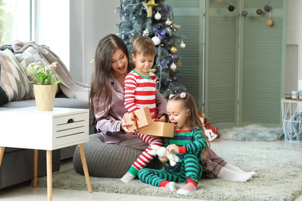 Mulher e seus filhinhos com presente de Natal em casa — Fotografia de Stock