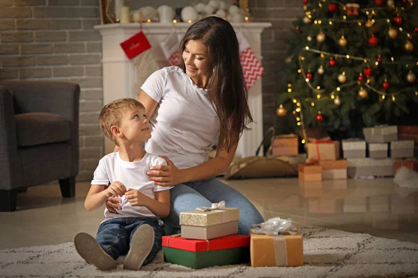 Женщина и ее маленький сын с подарками дома в канун Рождества — стоковое фото