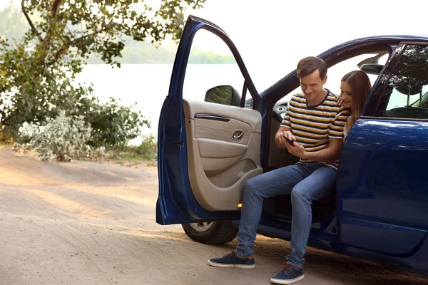 Happy couple using mobile phone for navigation in countryside — Stock Photo, Image