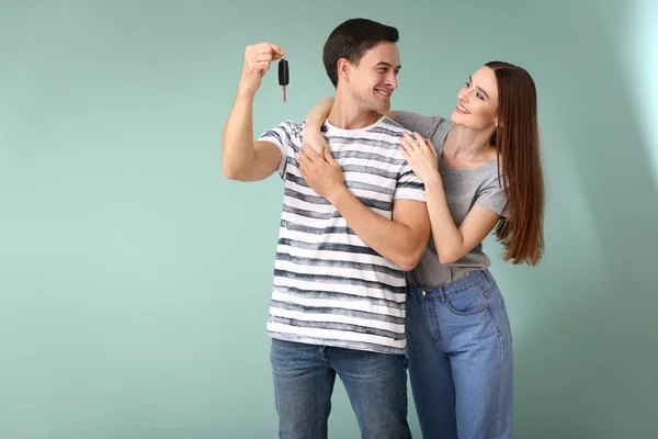 Happy par med nyckel från sin nya bil på färg bakgrund — Stockfoto