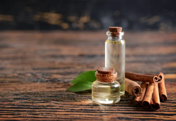 Aromatic cinnamon sticks and oil on wooden table — Stock Photo, Image