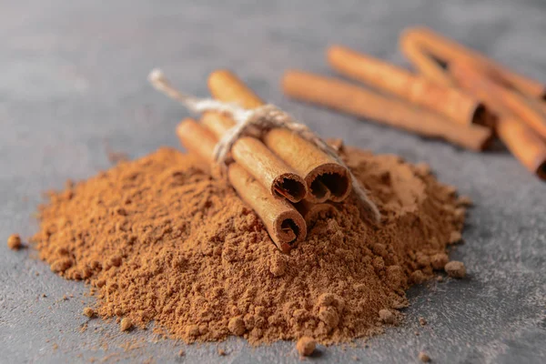 Paus de canela aromáticos e pó sobre fundo cinzento — Fotografia de Stock