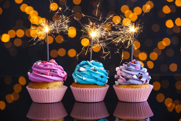 Chutné narozeninové koláčky na stole proti rozostčeným světlíkám — Stock fotografie