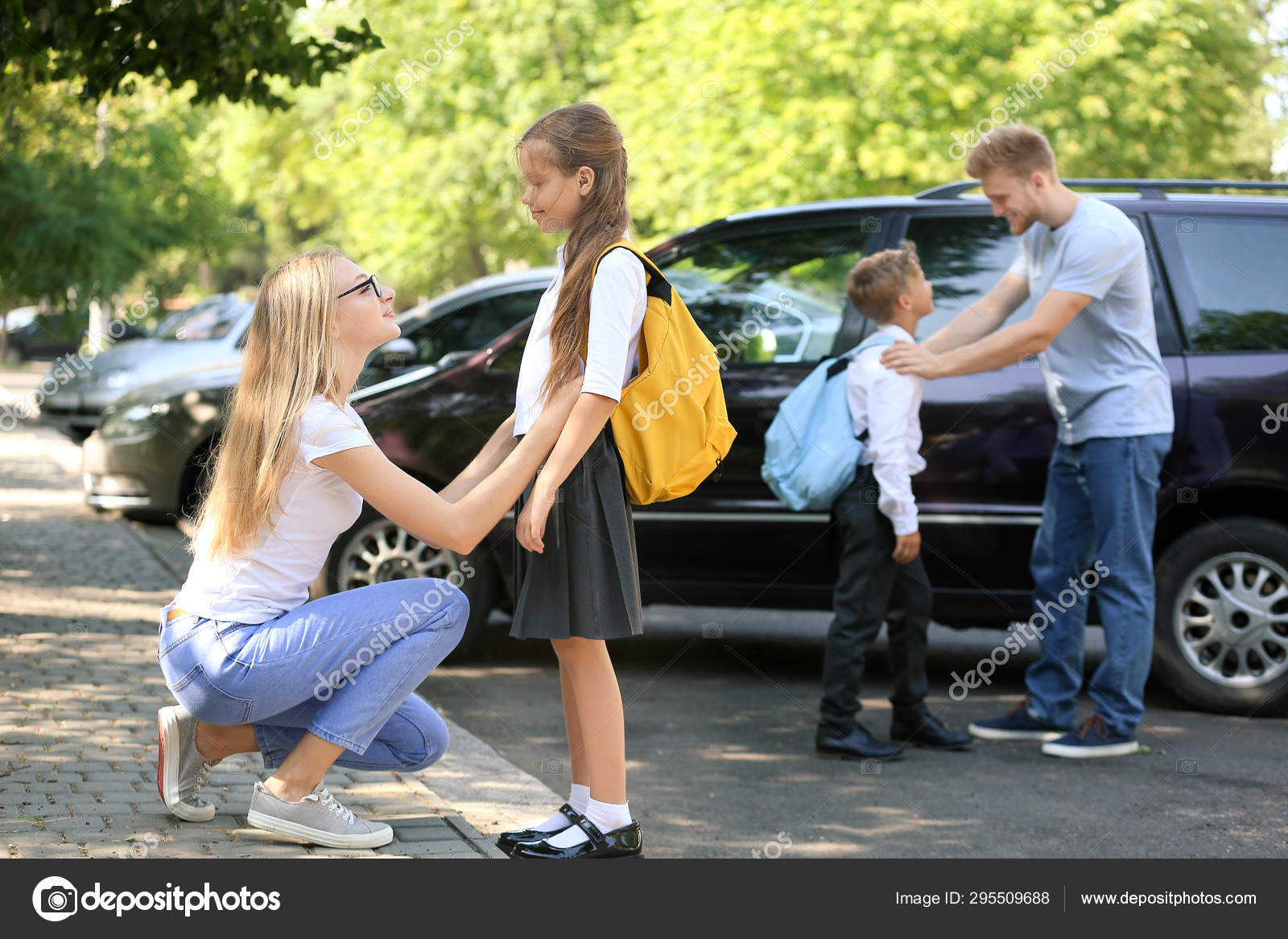 Parents saying goodbye to their children near school Stock Photo by