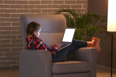 Dizüstü bilgisayar ile kız gece koltukta oturan