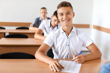 Sınıfta okul testini geçen genç çocuk
