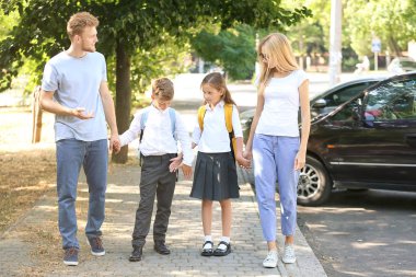 Küçük çocuklar ebeveynleri ile okula gidiyor
