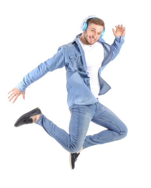 Jumping young man listening to music on white background — Stock Photo, Image