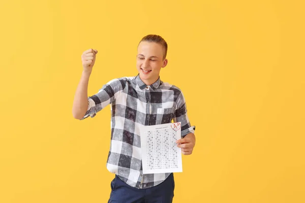 Menino feliz com resultados de teste escolar em fundo de cor — Fotografia de Stock