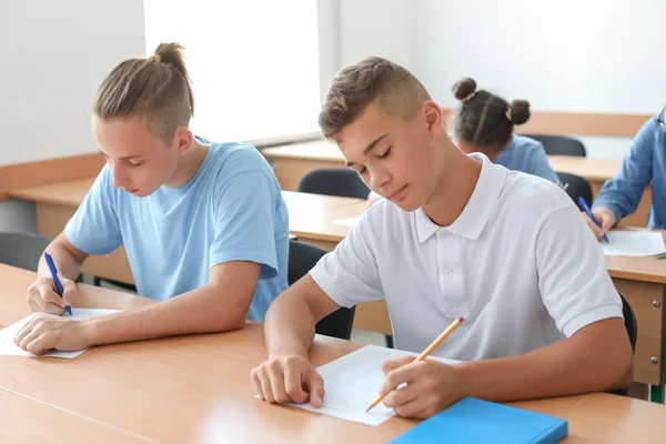 Adolescentes passando no teste escolar em sala de aula — Fotografia de Stock