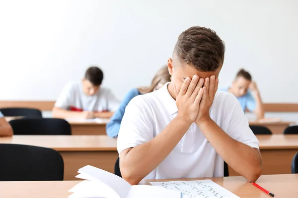 Menino infeliz passando no teste da escola em sala de aula — Fotografia de Stock