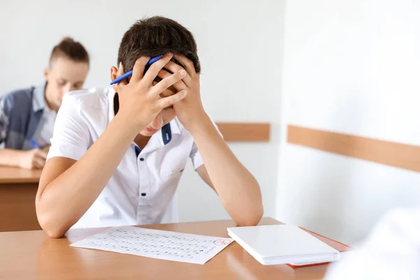 Troubled boy passing school test in classroom — Stock Photo, Image