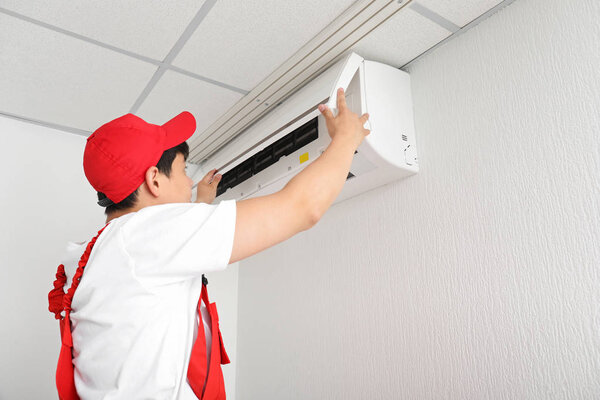 Electrician repairing air conditioner indoors