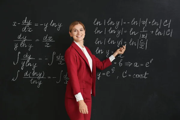 Bela professora de matemática perto de quadro negro em sala de aula — Fotografia de Stock