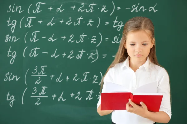 Gadis kecil dengan buku dekat papan tulis sekolah di kelas — Stok Foto