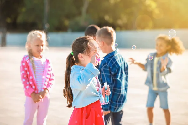 Cute girl blowing soap bubbles outdoors — Stock Photo, Image