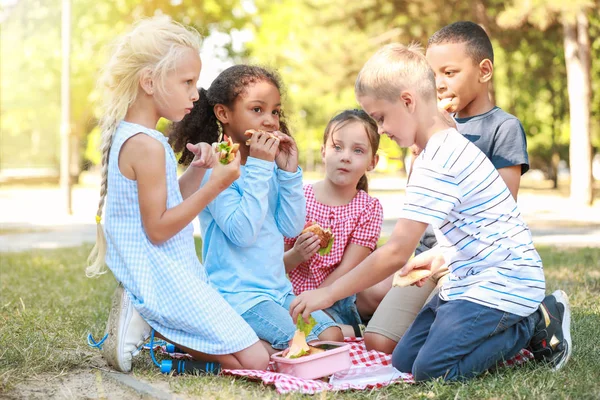 Nette kleine Kinder beim Mittagessen im Park — Stockfoto